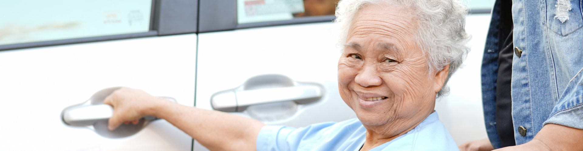 an old woman smiling while holding the door of a car